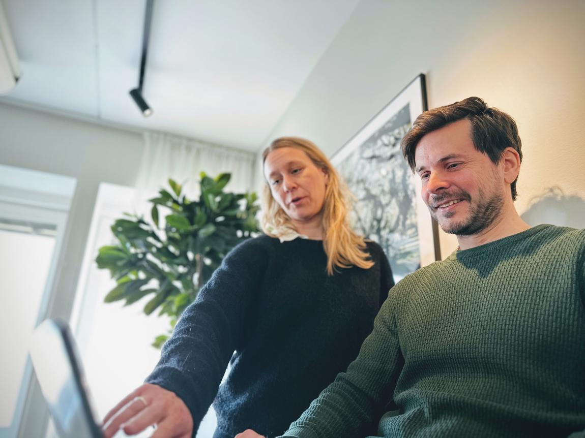 Två personer samarbetar vid en dator på kontoret.