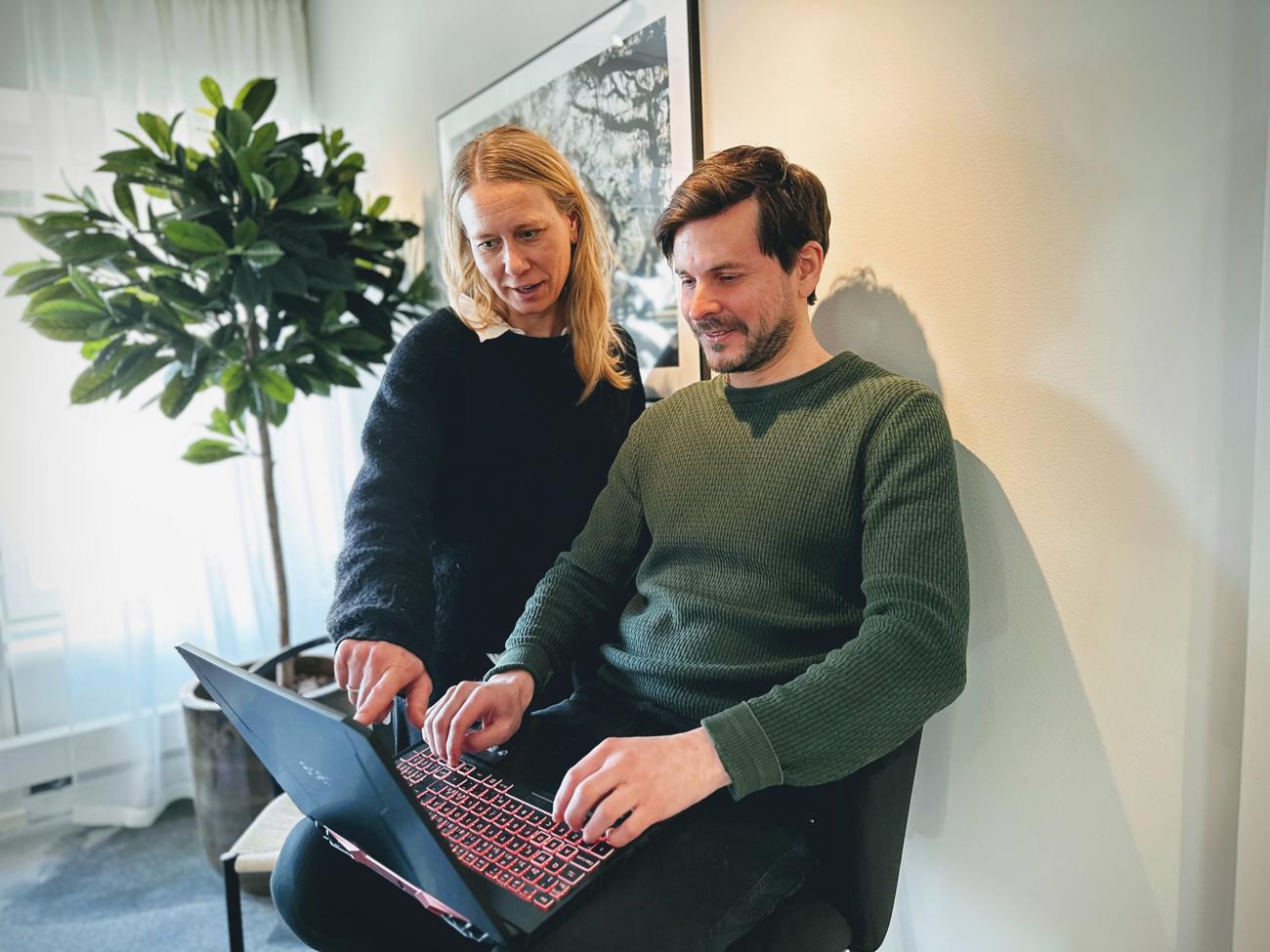 Två personer samarbetar vid en dator på kontoret.