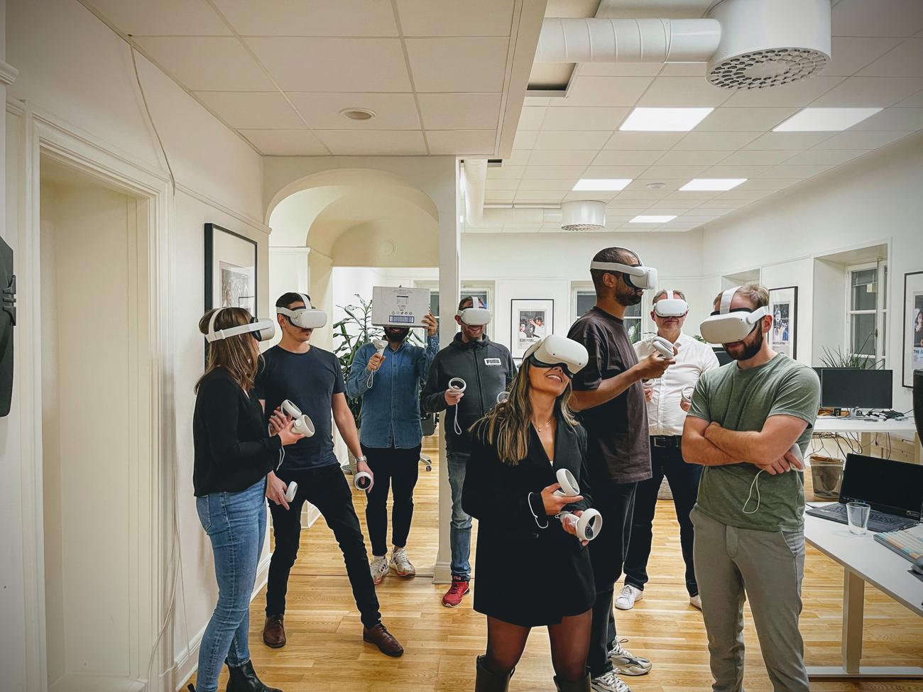 Grupp människor på ett kontor använder VR-headset och kontroller.