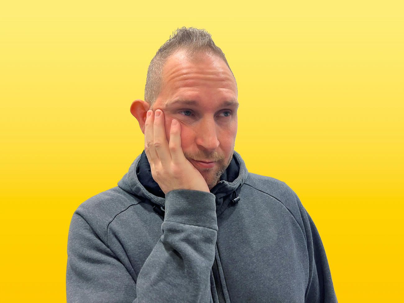 David med hand på kinden, ser fundersam ut, klädd i mörk hoodie.