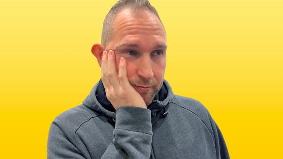 David med hand på kinden, ser fundersam ut, klädd i mörk hoodie.