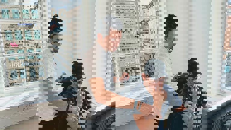 Kontorsmiljö med två kollegor som diskuterar arbete vid datorn.