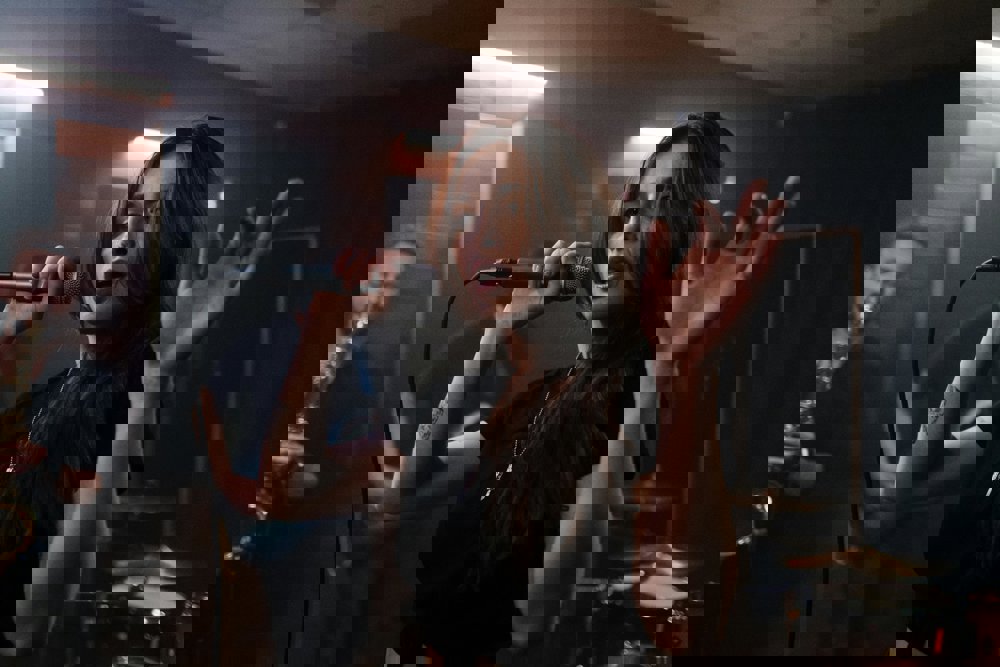 Intensiv scen med sångerska som framträder, bandmedlemmar i bakgrunden.