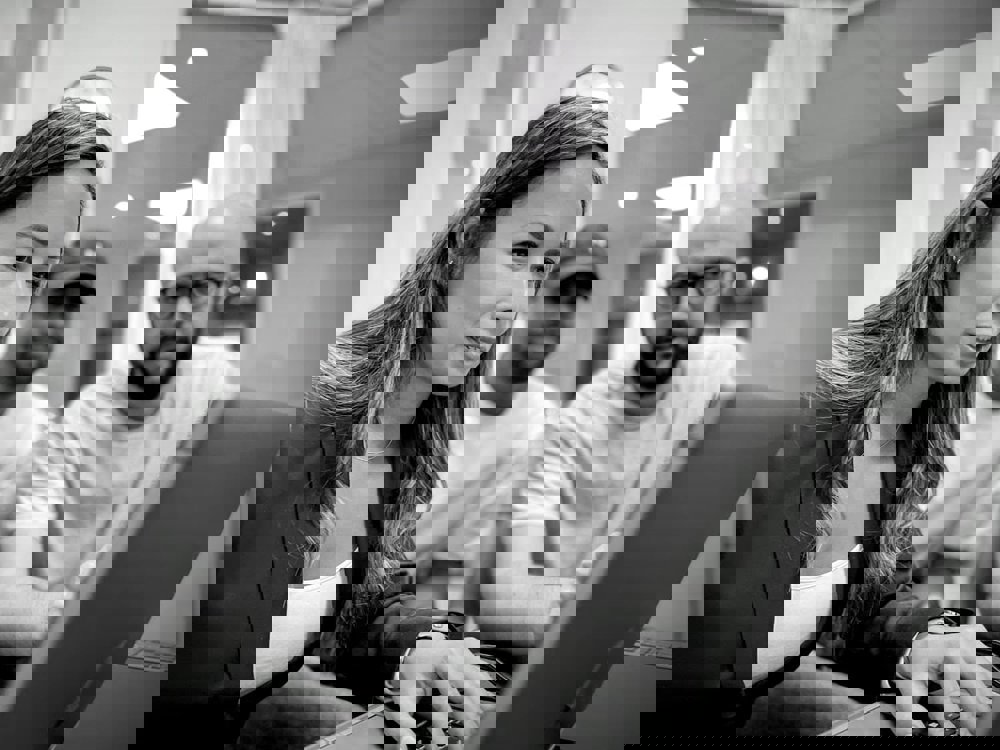 Tre personer samarbetar vid en dator i ett kontorsutrymme, fokuserade på skärmen.