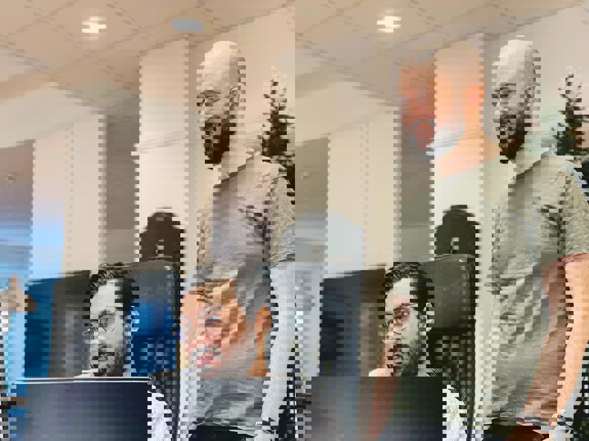 Två personer samarbetar vid en dator på kontoret.