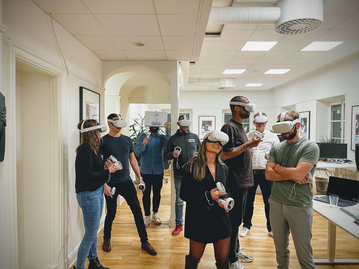 Grupp människor på ett kontor använder VR-headset och kontroller.